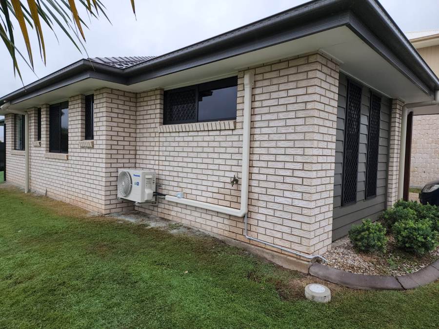 Air conditioning outdoor unit mounted on brick wall with tidy pipework