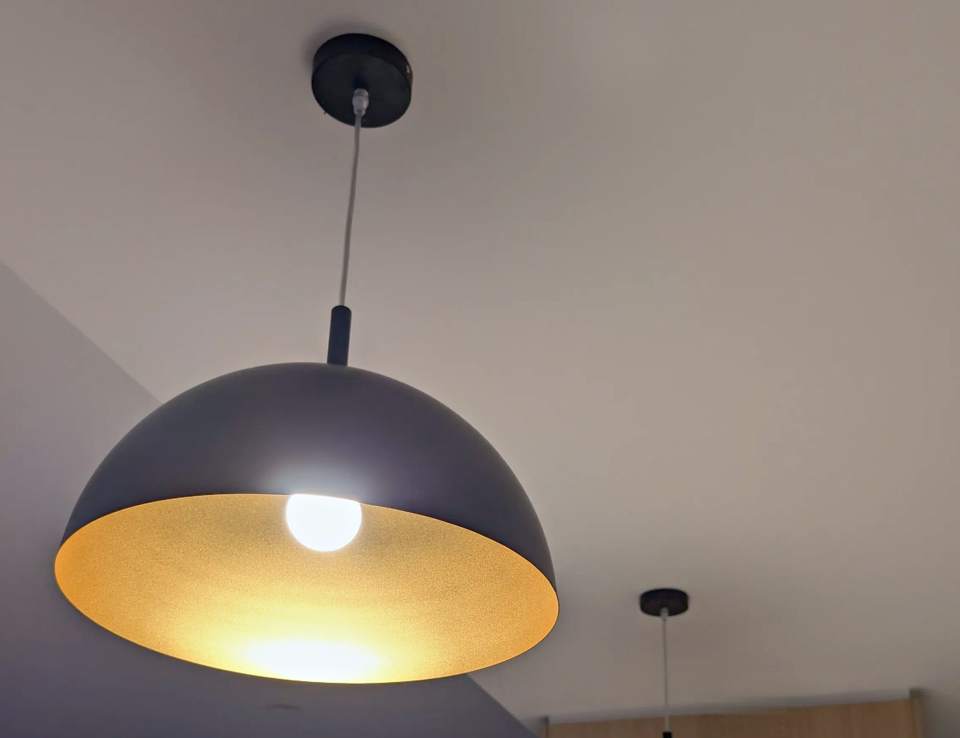 Black dome pendant lights installed over a kitchen